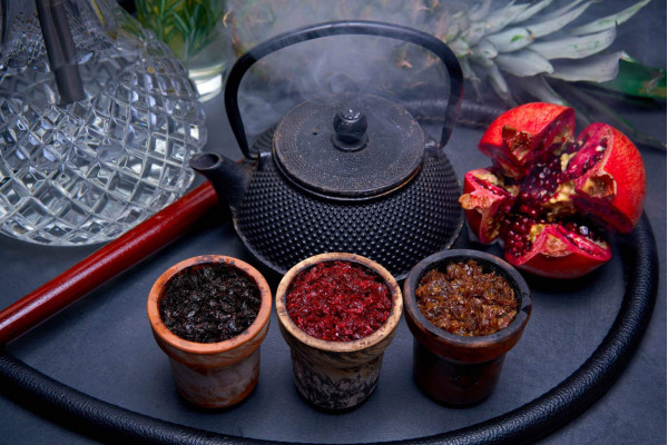 Банки с табаком для кальяна от разных брендов на фоне кальяна